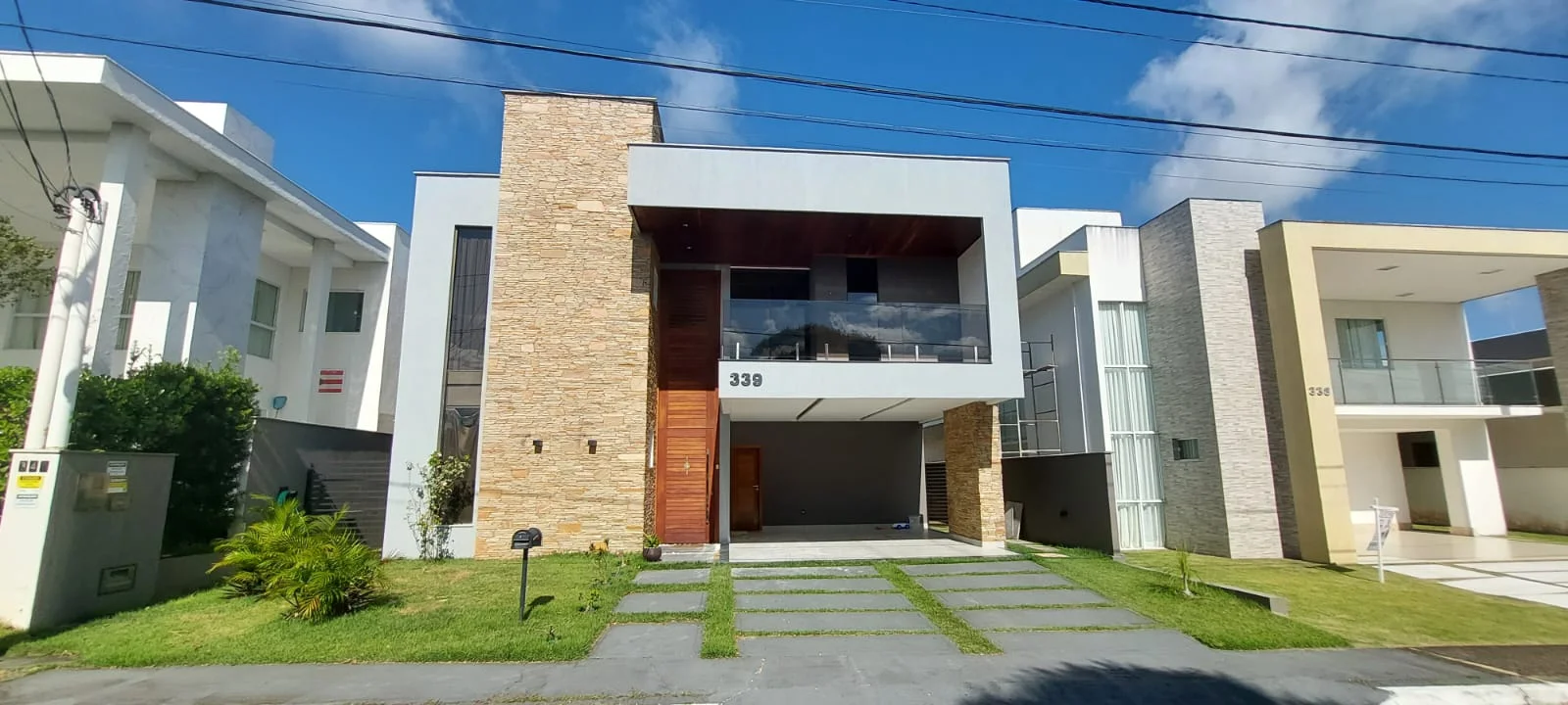 imagem mostra uma casa de alto padrão vista de frente, a casa tem dois andares e é possível ver que se encontra em um condomínio